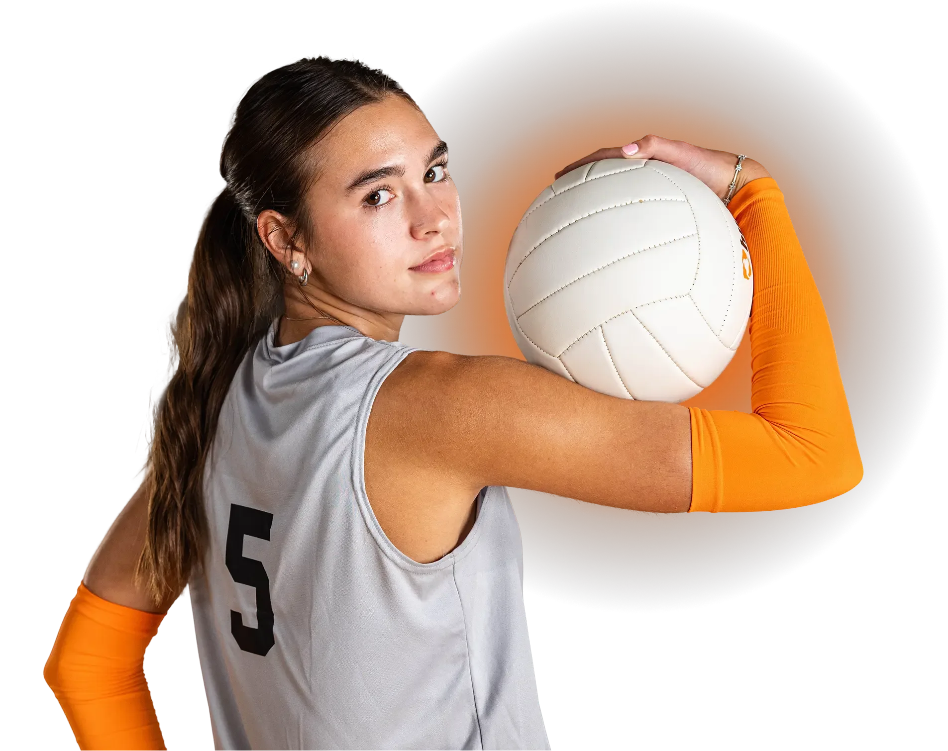 A female volleyball player holding a volleyball and looking at the camera