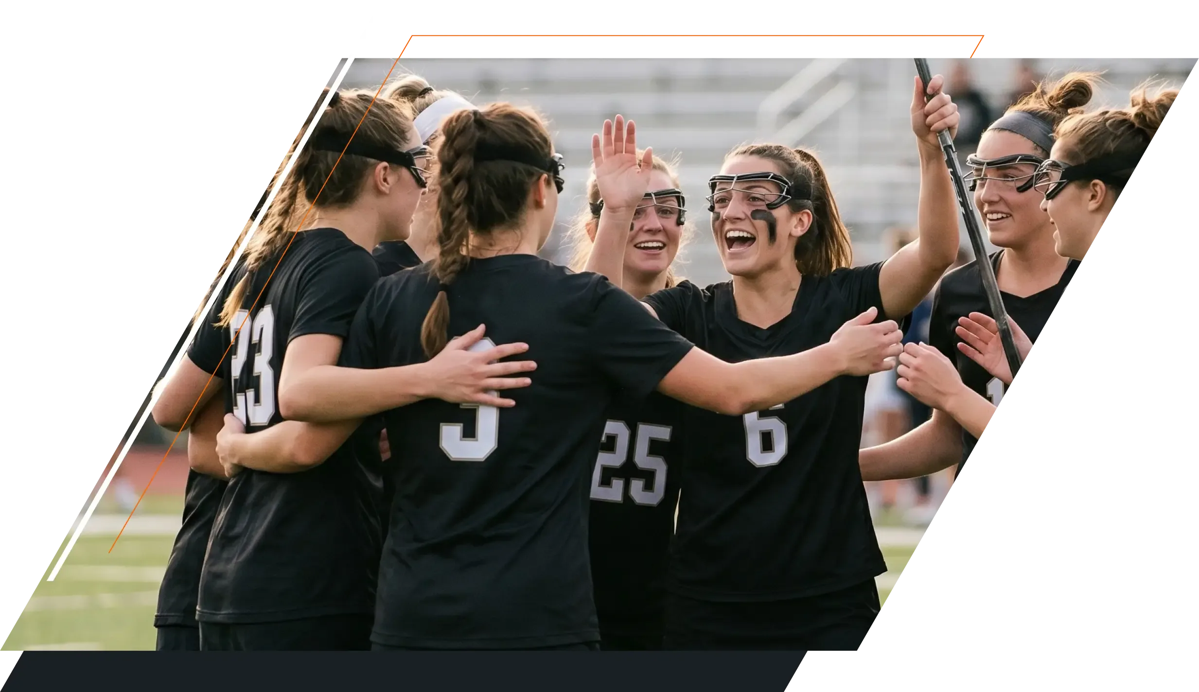 A group of smiling female lacrosse players wearing black jerseys and protective goggles celebrating together in a huddle on the field, set within a stylized, diagonally split dark frame.