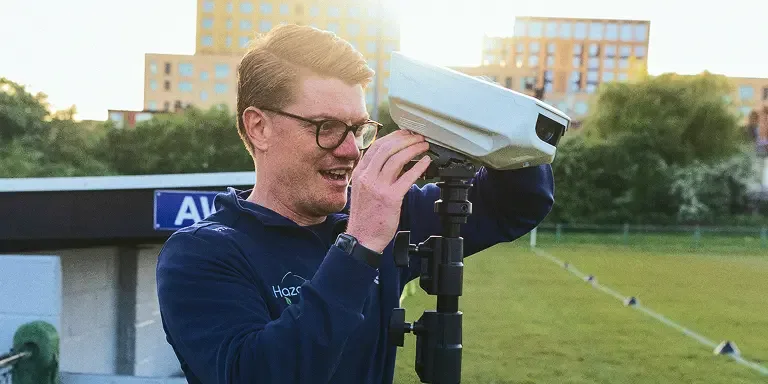 Photo of a coach setting up the Focus Flex camera on its tripod in preparation for practice.