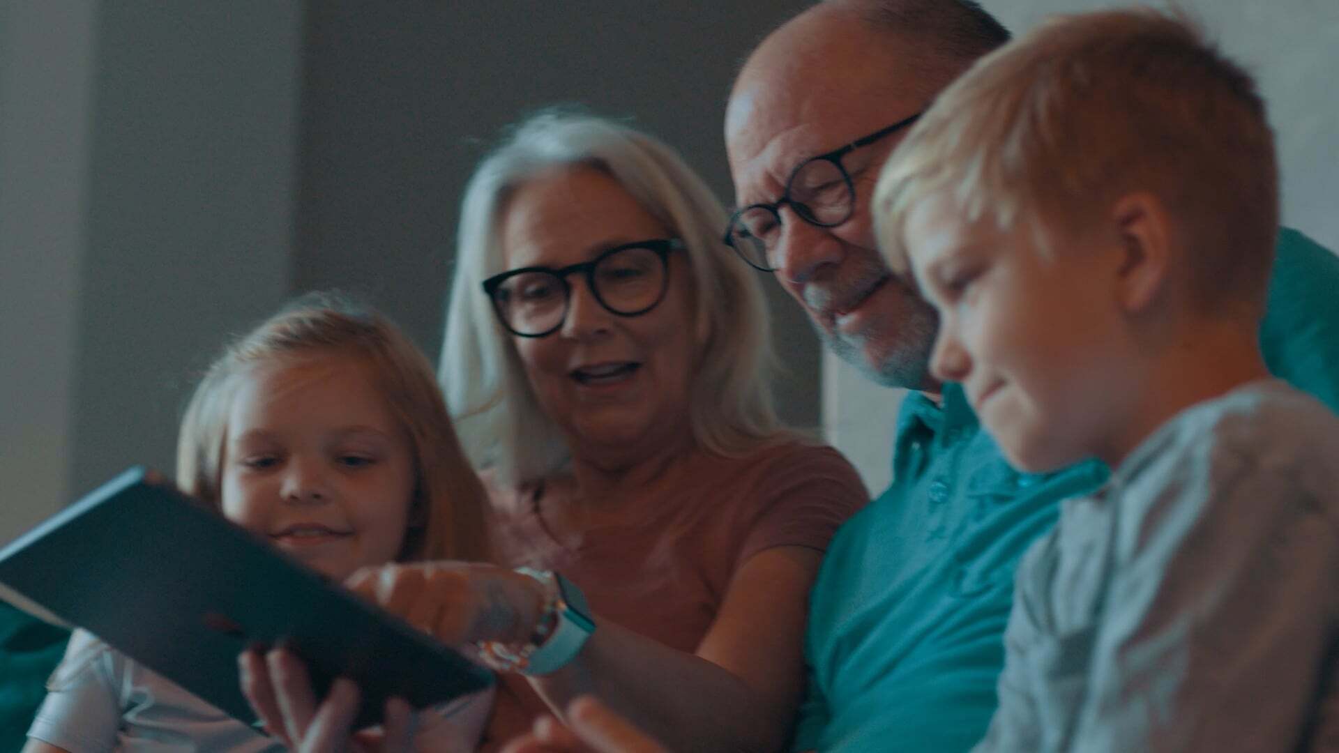 Video thumbnail: Two grandparents at home, sitting with two young children, browsing on a tablet.